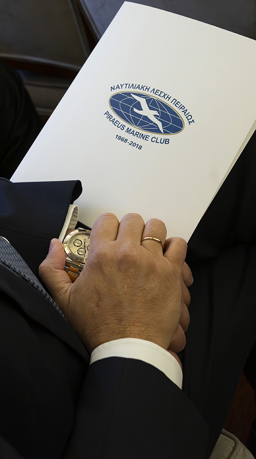 Man with a watch looking at a Piraeus marine club folder